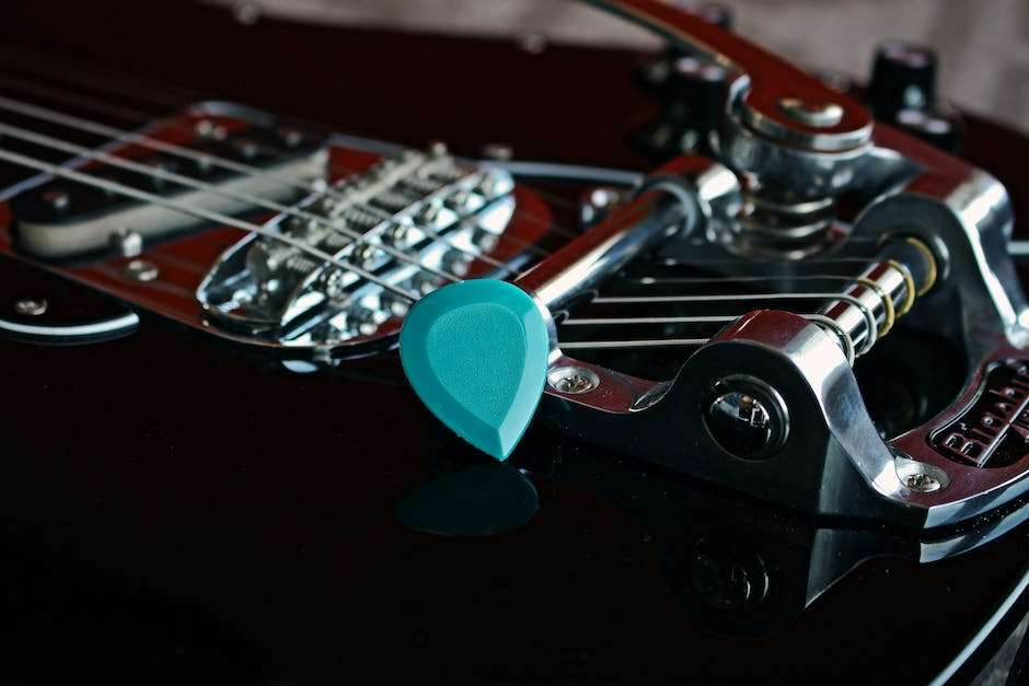 A photograph of a pearlescent celluloid guitar pick, reflecting light and showing its vibrant colors, giving a sense of its shimmering appearance and visual appeal.