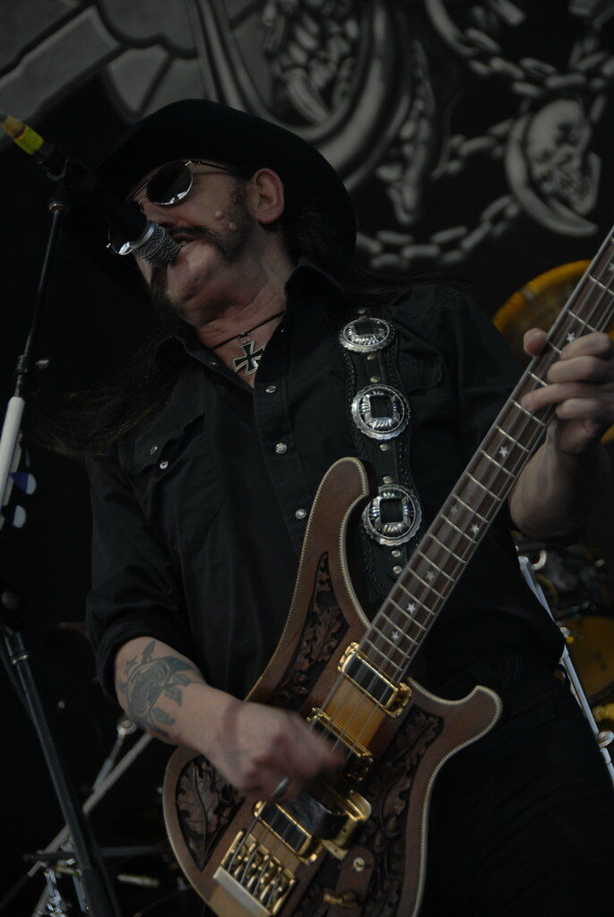 Close-up portrait of Lemmy Kilmister of Motörhead wearing his signature black cavalry hat, iron cross necklace, and denim vest